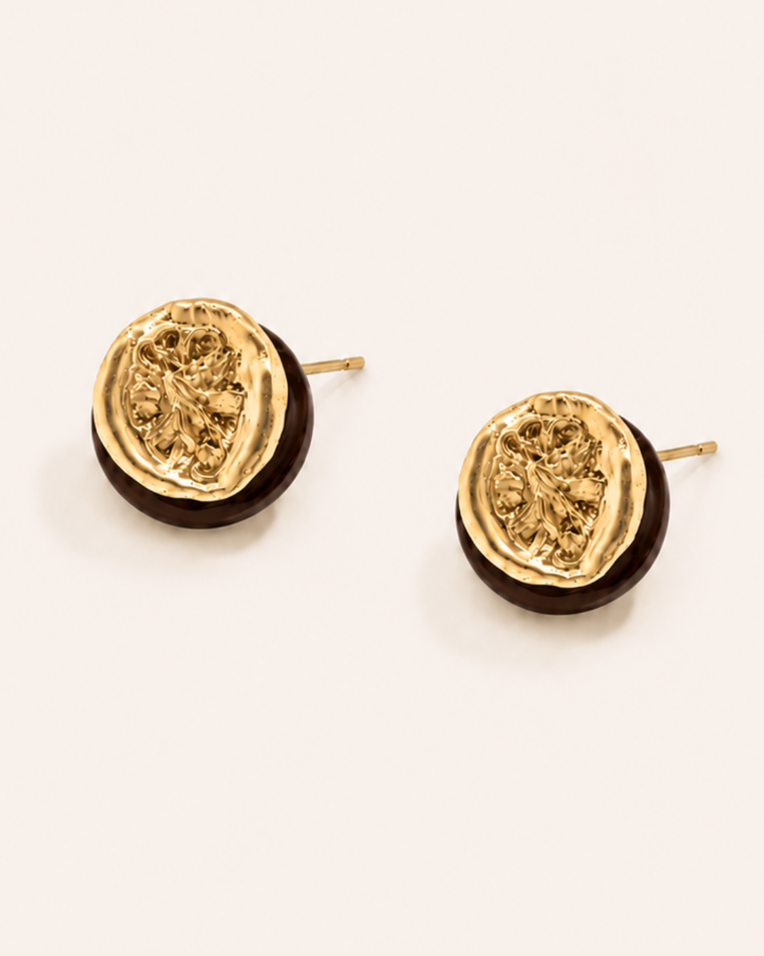 A pair of waterproof gold earrings on a plain background